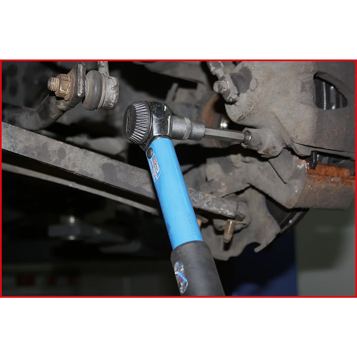 Eine Nahaufnahme eines blauen Werkzeugs, das an einem Autoteil verwendet wird. Der Schraubenschlüssel wird zum Schrauben gelöst.